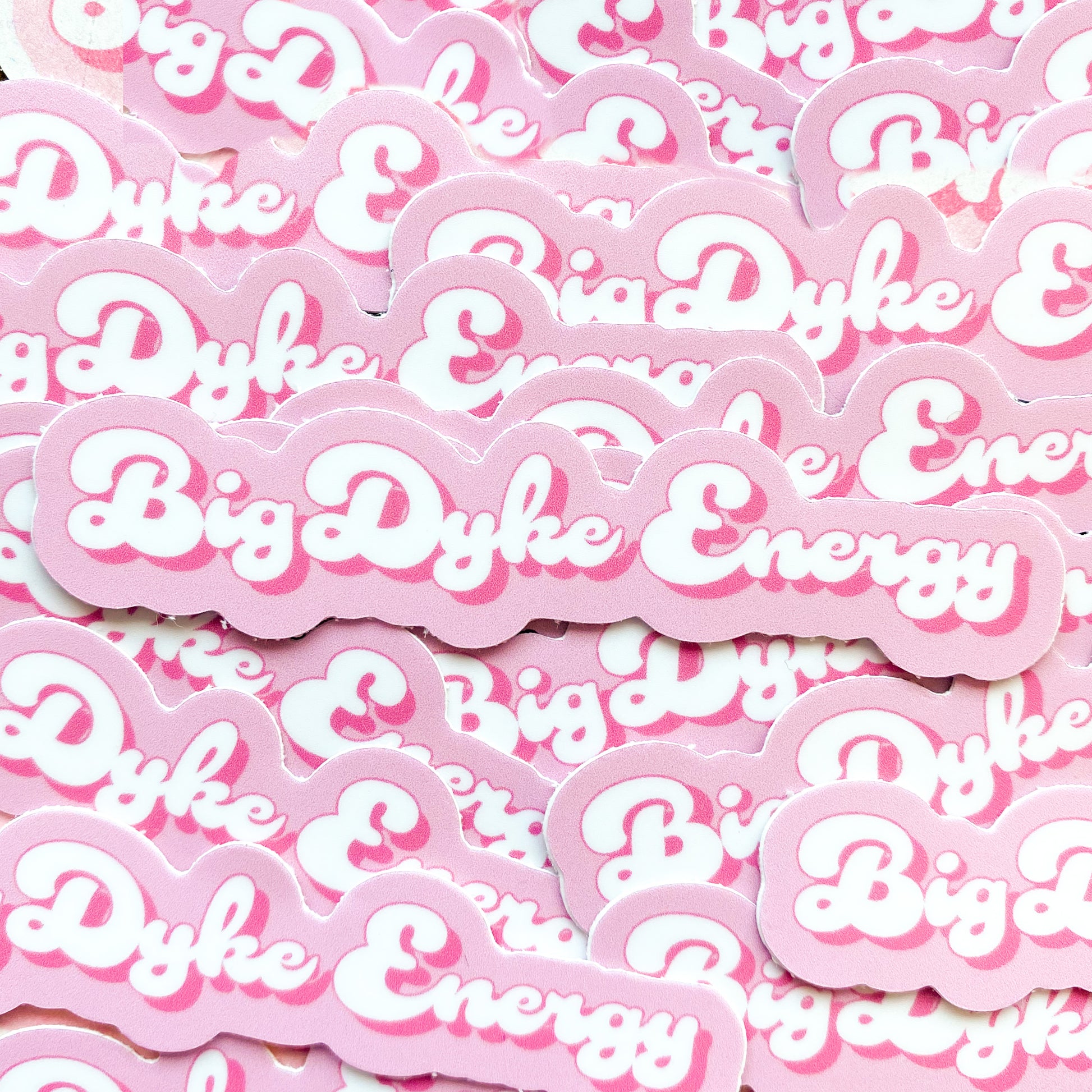 Photo of pink and white sticker with the  words 'big dyke energy', a funny lesbian pun.